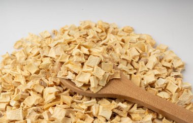 Kuru maydanoz kökü yığını izole edilmiş, kurutulmuş kereviz küpleri dağınık küçük meyan kökü parçaları, beyaz arka planda kuru sebze taneleri.