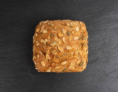 Kabak tohumlu ekmek, pepita tohumlu kahvaltı ruloları. Fitness karesi çöreği, sağlıklı hamburger, kabak tohumlu çörek, siyah arka plan manzaralı.