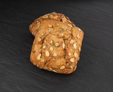 Balkabağı tohumu ekmeği, pepita tohumlu iki kahvaltı rulosu. Fitness karesi çöreği, sağlıklı hamburger, kabak tohumlu çörek, siyah arka plan manzaralı.