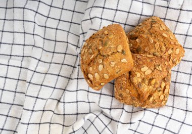 Balkabağı tohumlu ekmek, pepita tohumlu üç rulo kahvaltı. Fitness Square Bun, sağlıklı burger, kabak tohumlu çörek kırsal masa örtüsü arkaplan manzarası