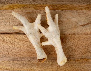 Kuru tavuk patileri ahşap kesme tahtasında evcil hayvan mamaları, kemikleri ve eti olan doğal köpek mamaları.