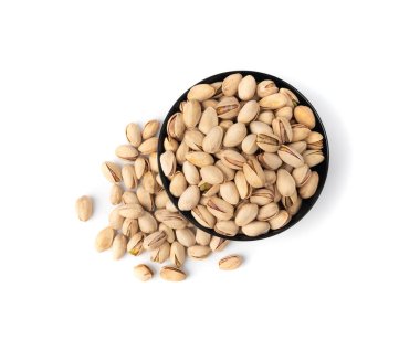Siyah kasede kızartılmış şam fıstığı. Pişmiş şam fıstığı yığını, kavrulmuş yeşil şam fıstığı meyvesi kabuklu beyaz arka plan manzaralı