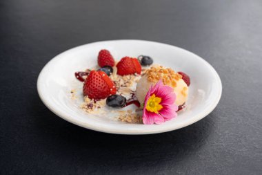 Meyveli mochi pirinç keki, beyaz daifuku, Japon geleneksel tatlısı, kremalı ve anko dolgulu yuvarlak wagashi, çilekli Asya şekeri, yaban mersini ve siyah arka planda çiçek.