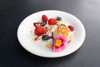 Meyveli mochi pirinç keki, beyaz daifuku, Japon geleneksel tatlısı, kremalı ve anko dolgulu yuvarlak wagashi, çilekli Asya şekeri, yaban mersini ve siyah arka planda çiçek.