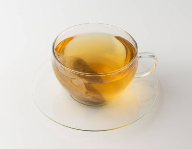 Cam bardakta bitkisel çay kesesi izole edilmiş, papatya çayı ve hiperikum ile sıcak su veya St. John 's Wort çay poşeti, tedavi amaçlı tıbbi içecek kupası, beyaz arka planda çay poşeti demleme işlemi