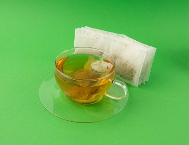 Fincanda bitki çayı kesesi, papatya çayı ve hiperikum ile sıcak su veya St. John 's Wort çay poşeti, tedavi amaçlı tıbbi içecek kupası, yeşil arka planda çay poşeti demleme süreci.