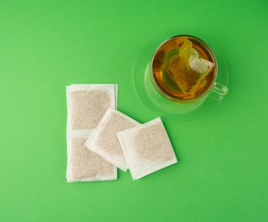 Fincanda bitki çayı kesesi, papatya çayı ve hiperikum ile sıcak su veya St. John 's Wort çay poşeti, tedavi amaçlı tıbbi içecek kupası, yeşil arka planda demleme işlemi