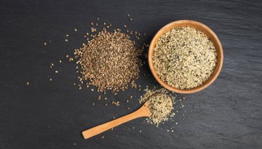 Kabuklu kenevir tohumları ahşap kasede, soyulmuş kenevir taneleri, kabuksuz marihuana çekirdekleri, siyah arka plan görünümlü yağ protein keneviri çekirdekleri