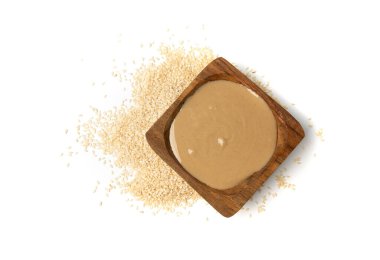 Tahini kasede izole edilmiş, susam tohumu ezmesi sürülmüş tahina sosu, doğu sosu, geleneksel doğu mutfağı malzemesi, beyaz arka planda yer susamı.
