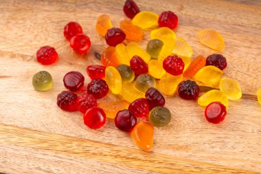 Meyveli şeker yığını yakın plan, vejetaryen marmelat çiğneme hapları, jelibon yığını, ahşap arka planda renkli jelatin şekerler.