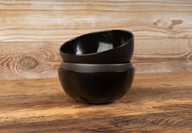 Masada boş kase yığını, ahşap masa üstünde siyah tabak, siyah porselen çanak modeli, metin için fotokopi alanı olan kırsal mutfak afişi.