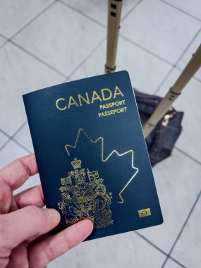 Havaalanının arka planında bavulu olan biri tarafından tutulan bir Kanada pasaportu. Seyahat, göç ve kimlik temaları için mükemmel.