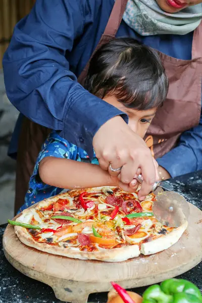 Komik aile çocuğu ve annesi mutfakta akşam yemeği için pizza yapıyor. Mutlu aile birlikte.