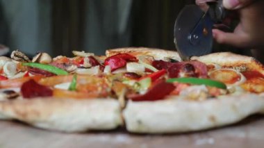 Çizgili kesme tahtasında pizza kesme makinesiyle pizza kesme