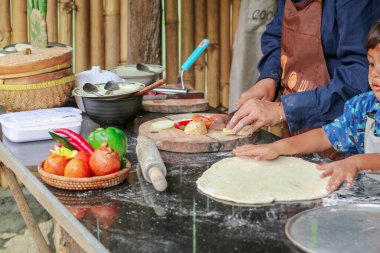 Mutlu aile ebeveyni anne küçük çocuğa fırın yapmayı öğretiyor, küçük tatlı çocuk merdaneyi tutuyor, annesine mutfakta pasta ya da bisküvi yaparken yardım ediyor.