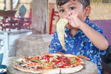 Küçük çocuk pizza yemekten hoşlanıyor..