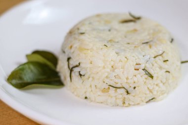 Tahta masada limon yaprağı pilavı. Üzerine kızarmış soğan. Bu, İtalyan tabağındaki Endonezya mutfağı. Nasi daun jeruk