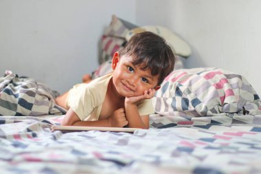 Dijital tablet bilgisayar kullanarak evde yatan üç yaşındaki Asyalı çocuk.