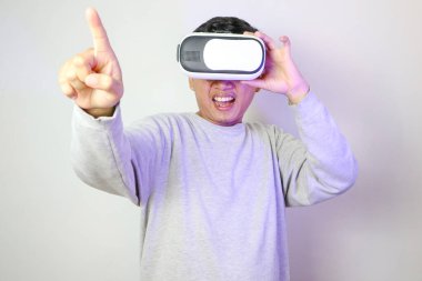 Heyecanlı genç Asyalı VR kulaklık takıyor ve web pankartı gri arka planında yeri gösteriyor.
