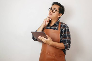 Önlük giyen Asyalı adam tablet tutuyor ve jest, kahve dükkanı ve restoran işletme konsepti gösteriyor.