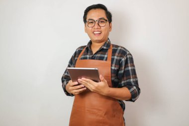 Önlük giyen Asyalı adam kameraya, kahveye ve restoran işletme fikrine bakıyor.