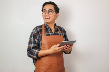 Asyalı adam elinde tabletle beyaz boşluğa bakıyor..