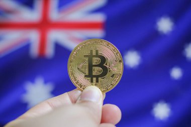 Avustralya bayrağının arka planında altın Bitcoin tutan adam.