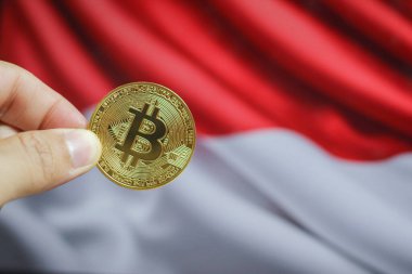 Altın Bitcoin bir adamın elinde, Endonezya bayrağı da arka planda.