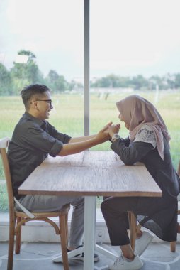 Romantik Müslüman çiftin portresi elleriyle kalp hareketi yapıyor, Sevgililer Günü 'nü kutlayan tesettürlü Arap erkek ve kadını seviyor, kameraya bakıyor ve gülümsüyor, bej arka planda poz veriyor.