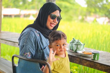 Mutlu Asyalı Müslüman aile hafta sonu geleneksel yemek ve içeceklerle, güzel Asyalı kadın Müslüman ve sevimli küçük çocuk portresiyle ve kameraya bakarak bir arada kalıyorlar..