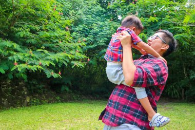 Mutlu baba ve oğul. Baba çocuğunu gün batımında gökyüzüne kaldırıyor. Babalık ve ebeveynlik kavramı.