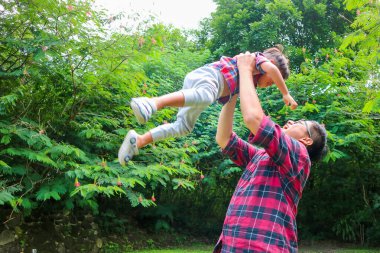 Mutlu baba ve oğul. Baba çocuğunu gün batımında gökyüzüne kaldırıyor. Babalık ve ebeveynlik kavramı.