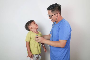 Klinikteki yakışıklı Asyalı doktor ve genç çocuk kalp atışlarını izliyor.