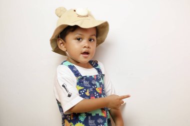 Gülümseyen mutlu Asyalı 2-3 yaşındaki çocuk beyaz arka planda izole edilmiş fotokopi alanını işaret ediyor.