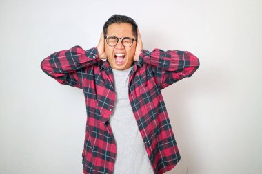 Duygu sömürüsü yapan, elleri kulaklarında genç Asyalı bir adam beyaz stüdyo arka planında yalnız başına dikilirken bağırıp çağırmak ve el kol hareketi yapmak istemiyor.