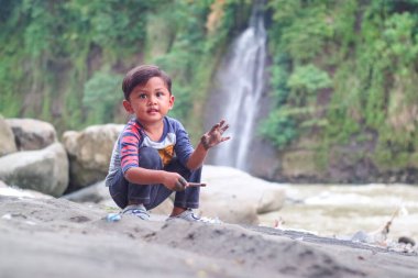 Asyalı çocuk oyuncaklar ve doğal bir geçmişi olan kum oynuyor. Küçük bir çocuk için iyi bir motor beceri gelişimi. Yumuşak odaklanma. Boşluğu kopyala.