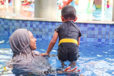 Anne ve bebek havuzda yüzüyor.
