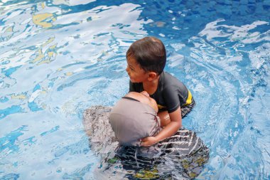 Mutlu çocuk ve kadın yüzme havuzunda oynuyorlar. Yaz tatili kavramı