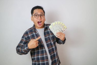 Pozitif Asyalı adam gülümseyip elinde bir sürü para olduğunu işaret ediyor.
