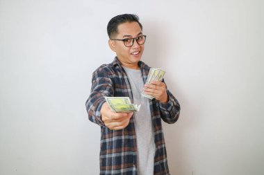 Elinde para banknotları tutan gülümseyen Asyalı adam ve kamerayı işaret eden Asyalı adamın sana para verdiği ifadesi. Asyalı adam senin için para veriyor..