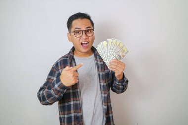 Pozitif Asyalı adam gülümseyip elinde bir sürü para olduğunu işaret ediyor.