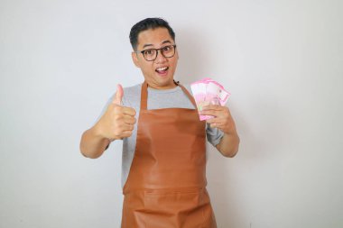 Önlük takan, gülümseyen ve elinde para tutan bir adam.