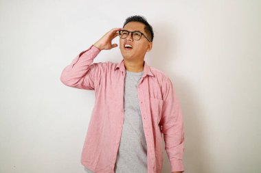 Genç adam pembe gömlek kaşınıyor. Kafası karışmış ve kafası karışmış.