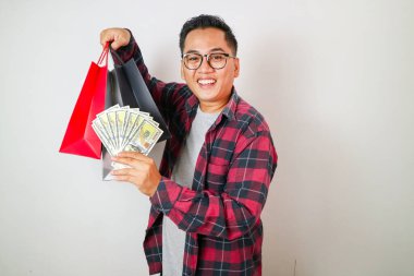 Elinde para ve alışveriş torbaları tutan Asyalı genç bir adamın portresi.
