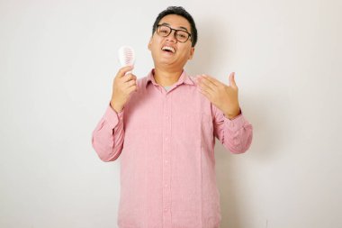 Yetişkin Asyalı adam elektrikli yelpaze kullanıyor ve sıcak bir jest yapıyor.