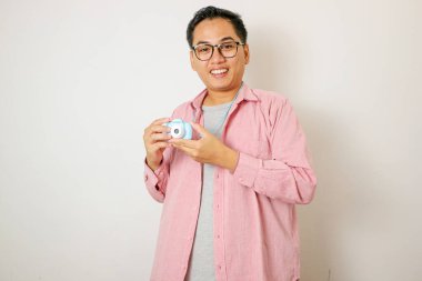 Yakışıklı genç fotoğrafçı gülümsüyor ve elinde profesyonel dijital kamerayla stüdyoda poz veriyor..