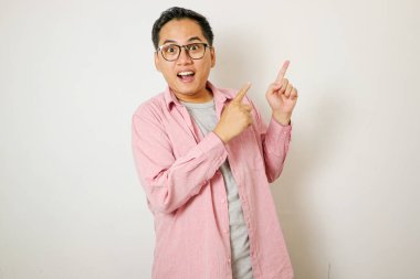 Yetişkin Asyalı adam gülümseyen yüzüyle parmağını sola gösteriyor.