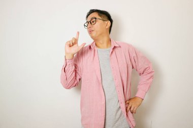 Beyaz arka planda duran genç Asyalı adam sembolik bir silahla el hareketleriyle cinayet silahlarıyla oynuyor, kızgın surat.