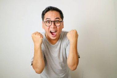 İki yumruğunu sıkmış heyecanlı Asyalı genç adam.