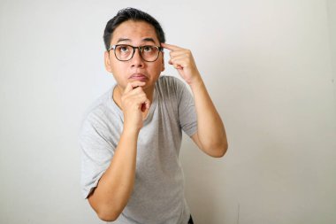 Alnını işaret eden genç bir adam, derin düşünce ya da konsantrasyon ifade eder, düz bir arka plan karşı.